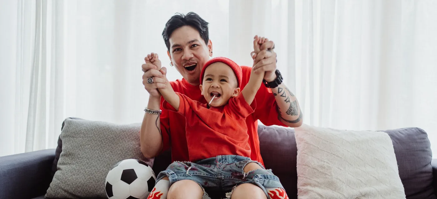 Teste IPTV Android: pai e filho comemorando um gol no sofá durante o teste grátis